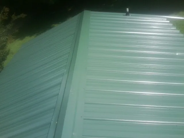 New green metal panels meeting at the ridge of a roof — Flat Roof Repair work by our crew in Brooklet