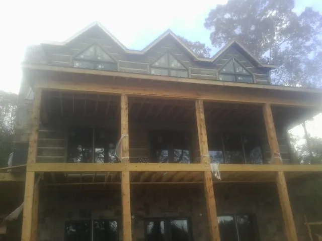 Dormers and porch framing on a large log home under construction — Roof Coating work by our crew in Brooklet