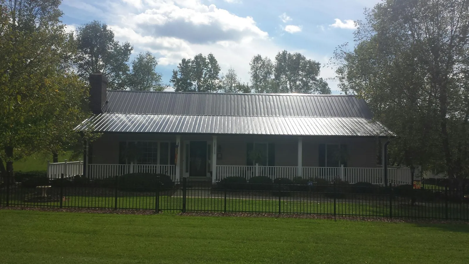 Gray metal roof on a brick ranch with a full width front porch — Gutter Guard Installation work by our crew in Brooklet